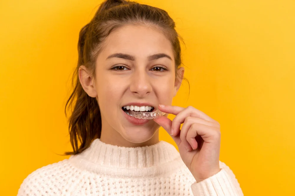 Smiling woman holding a clear aligner
