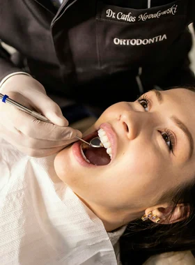 Dentist examining a smiling patient's teeth with a mirror